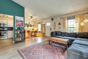 Un salon comprenant un canapé, une table basse, une bibliothèque et un coin repas avec une table et des chaises.