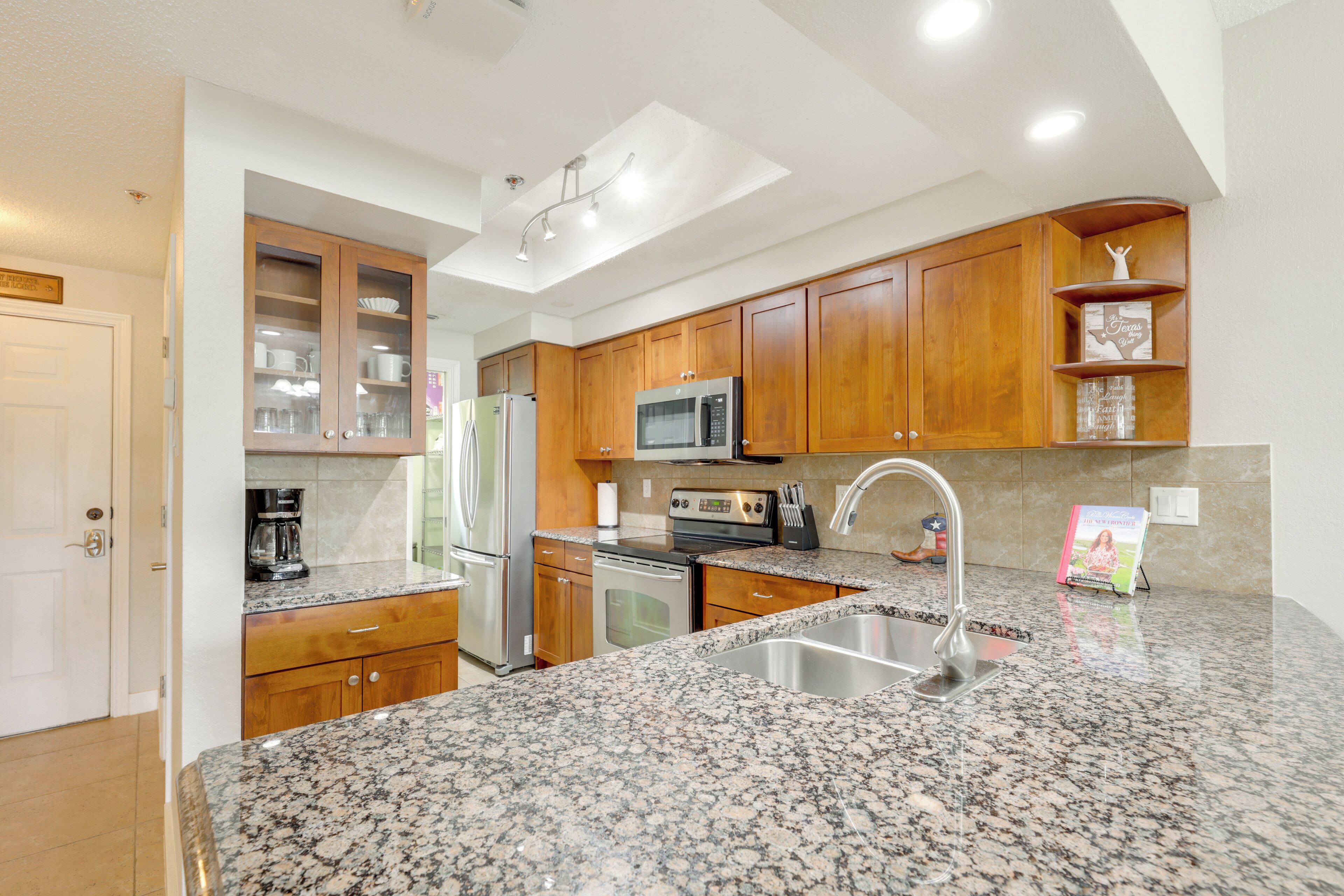 A kitchen with granite countertops, wooden cabinets, stainless steel appliances, and a built-in microwave.