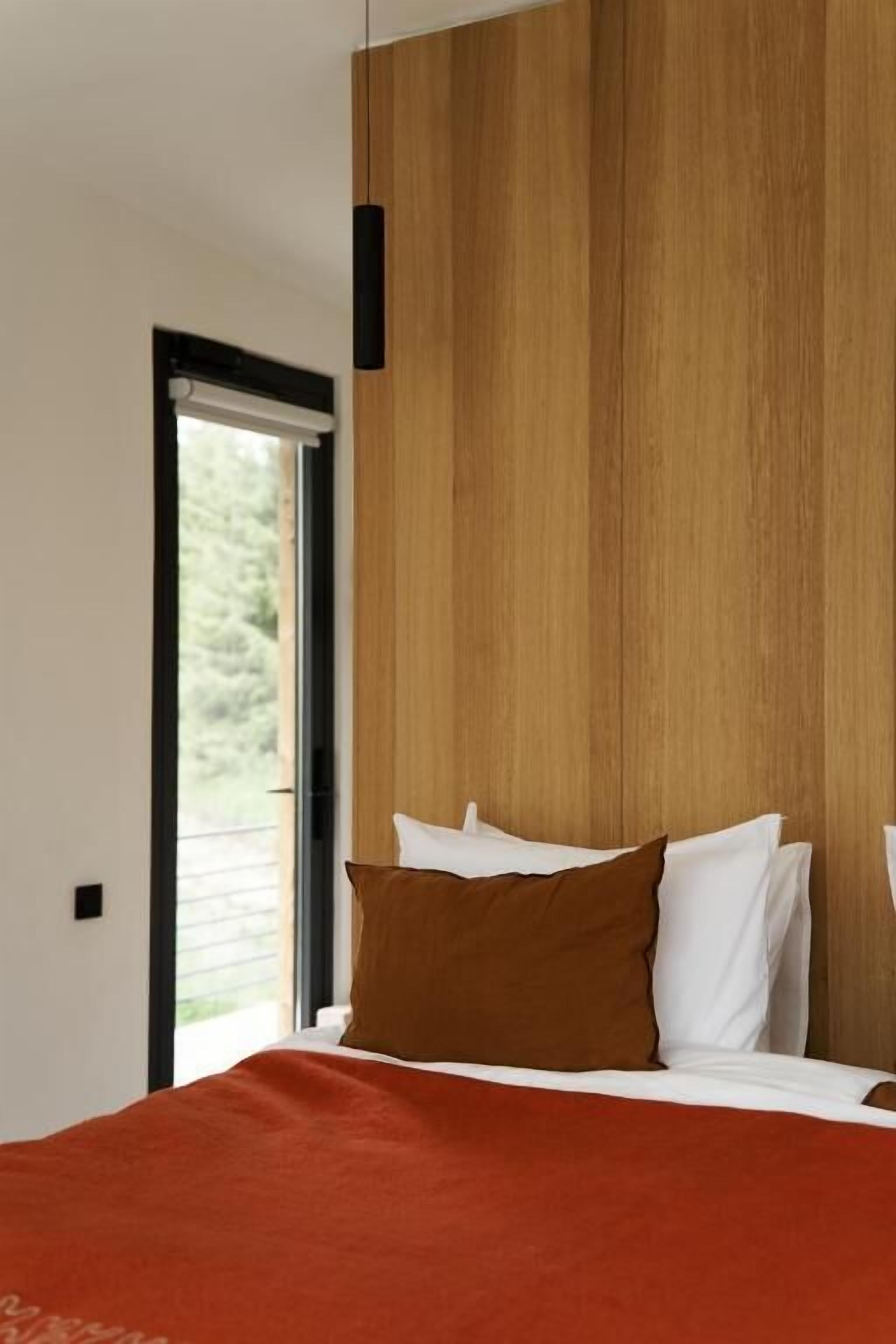 A bedroom with a bed, a window, and a wooden wall.