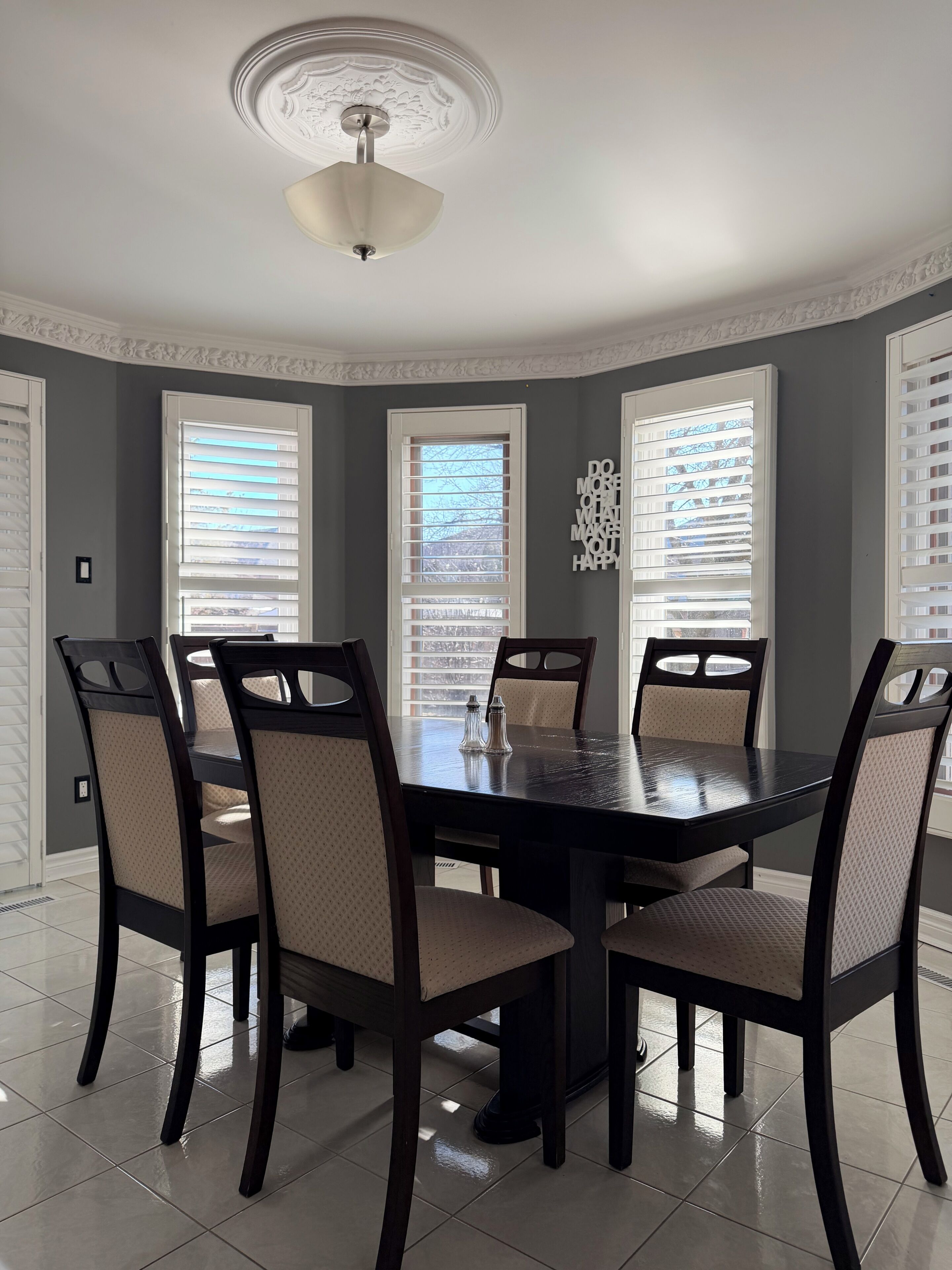 Une salle à manger avec une table ronde, six chaises et un luminaire au plafond.