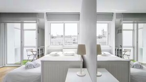 A modern hotel room with a large window, a bed, a small table, and a chair.