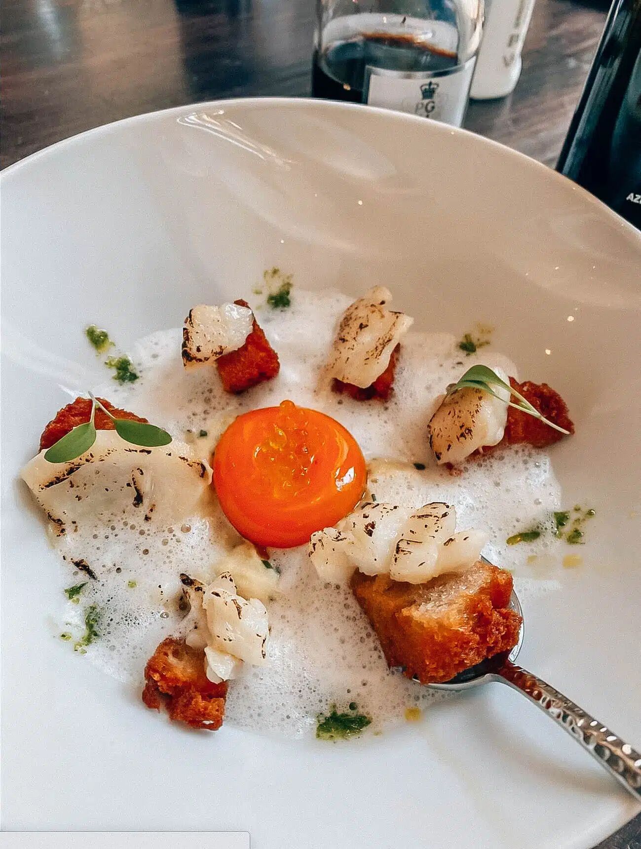 Un piatto di cibo con salsa cremosa, una fetta di pomodoro e verdure verdi.