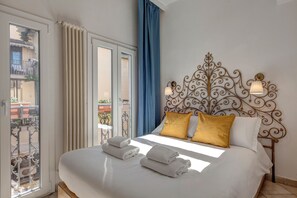 Ein Hotelzimmer mit einem großen Bett, zwei Kissen, einem Metall-Kopfschild und einem Balkon mit Geländer.