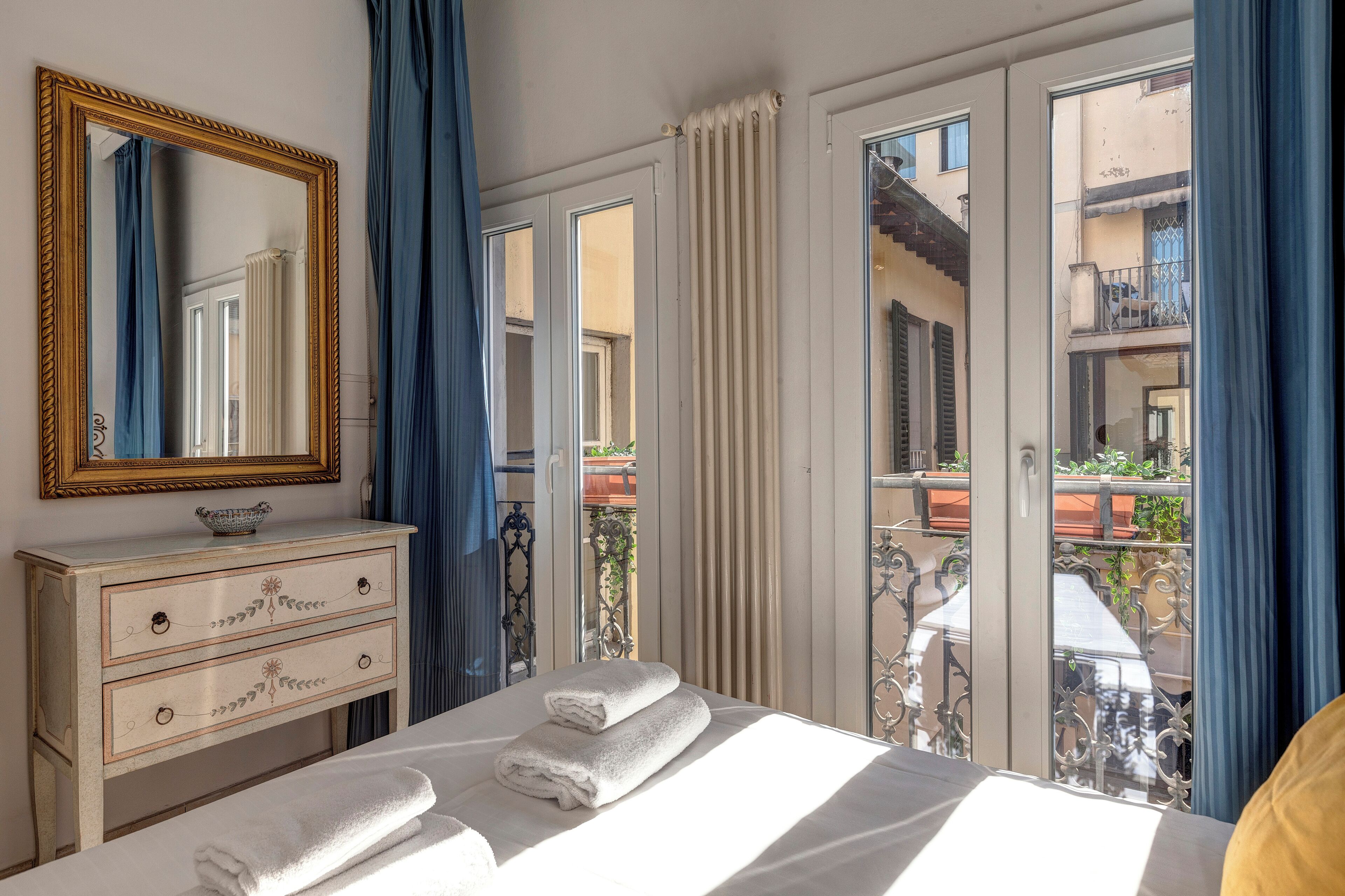 Un dormitorio con cama, cómoda, espejo y vistas al balcón.