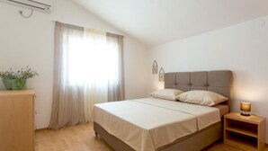 A bedroom with a bed, a nightstand, a lamp, a window with curtains, and a small plant. - Villa Anita – for 10 Guests with Private Pool, Okrug Donji (Okrug Donji)