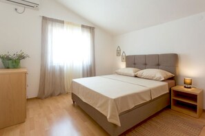 A bedroom with a bed, a nightstand, a lamp, a window with curtains, and a small plant. - Villa Anita – for 10 Guests with Private Pool, Okrug Donji (Okrug Donji)