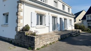 Ein zweistöckiges Gebäude mit Steinfundament, weißen Außenwänden und zahlreichen Fenstern mit Fensterläden.