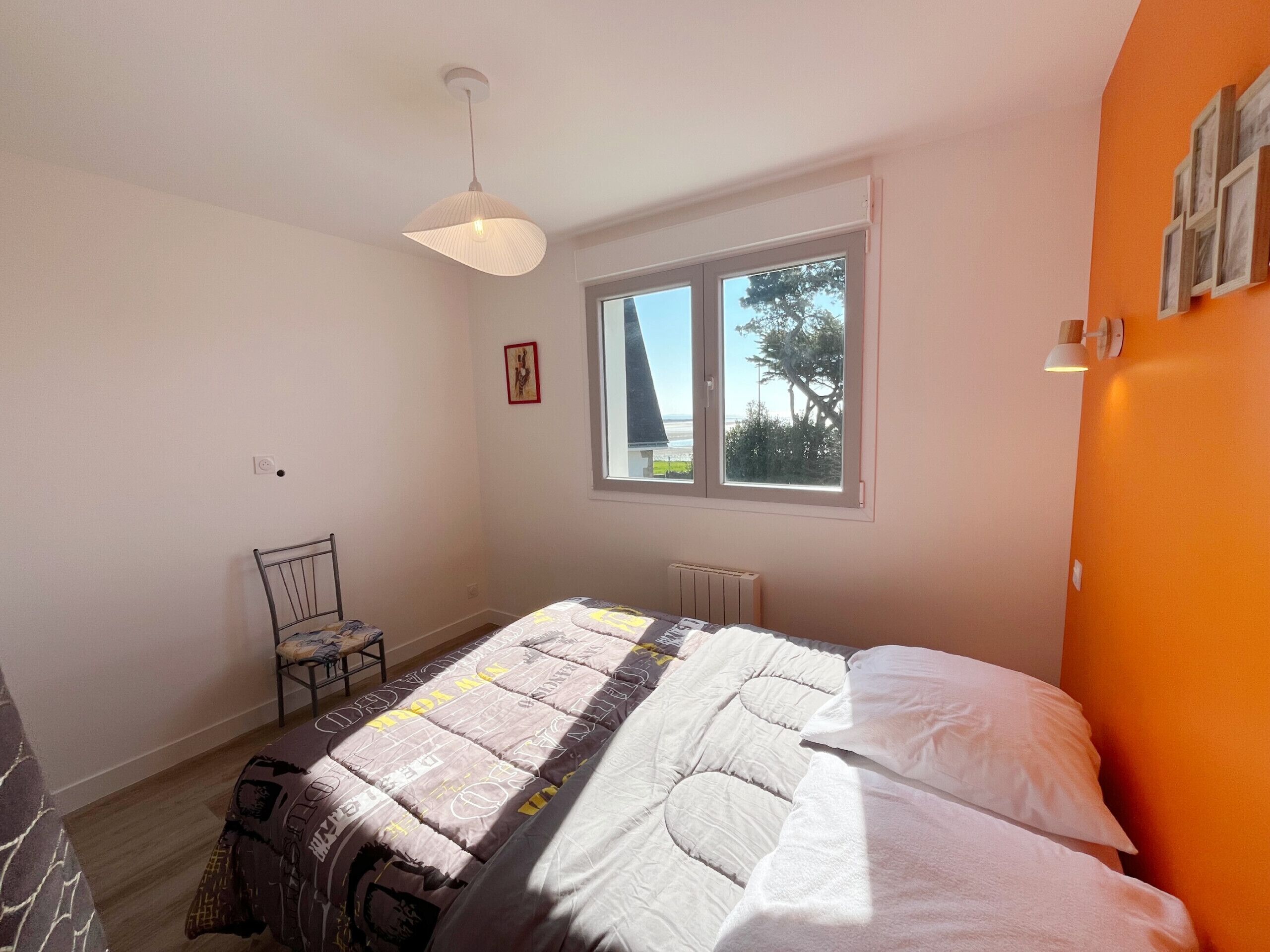 A bedroom with a bed, a chair, a window, and a radiator.