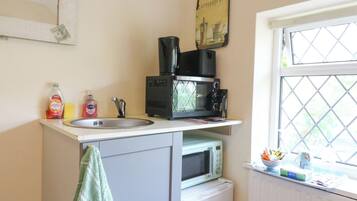 A compact kitchen with a sink, a microwave, and a small refrigerator.