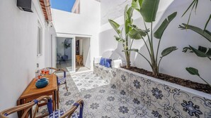 A patio area with a table and chairs, a tiled floor, and large plants. - Charming 3BR historic townhouse in Portimão's old town, steps from the marina and promenade. Easy access to Algarve beaches. Sleeps 9. Self check-in via lockbox. (Portimão)