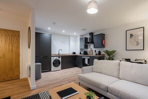 A modern apartment with a kitchen, a sofa, a dining table, and a small plant. - City Point Aberdeen by Guestz (Aberdeen)