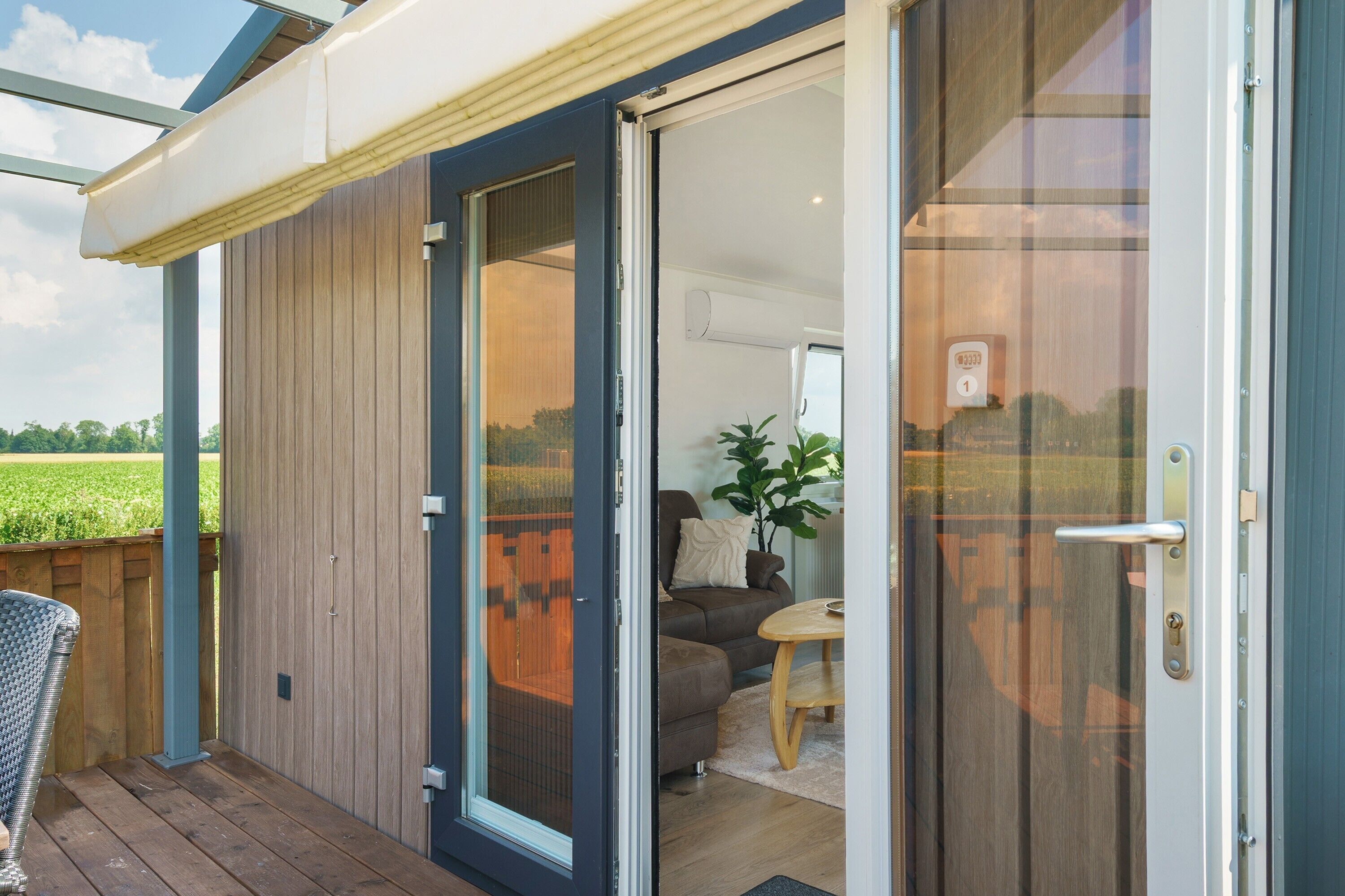 A modern house with a sliding glass door leading to a living room with a sofa and a small table.