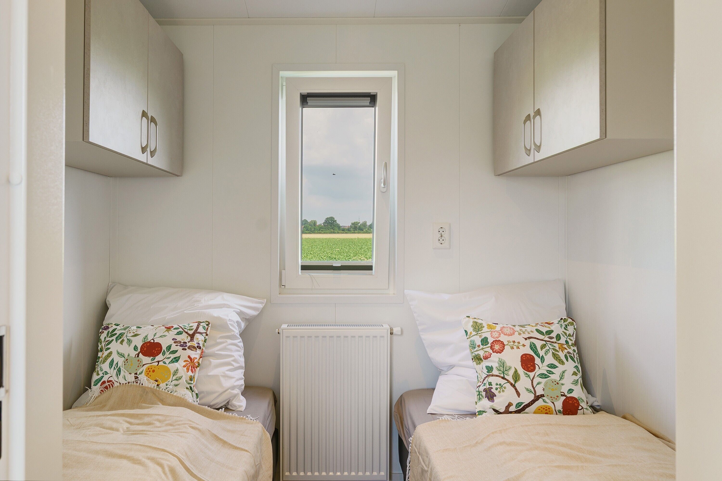 Eine kleine, einfache Unterkunft mit zwei Betten, einem Fenster und einer Heizung.