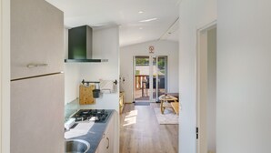 A narrow hallway leading to a kitchen with a stove, cabinets, and a dining area with a table and chairs.