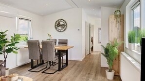 A modern kitchen with a dining table, chairs, and a clock on the wall.