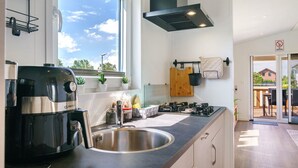 A modern kitchen with a stainless steel sink, a coffee maker, and a window with a view of the sky.