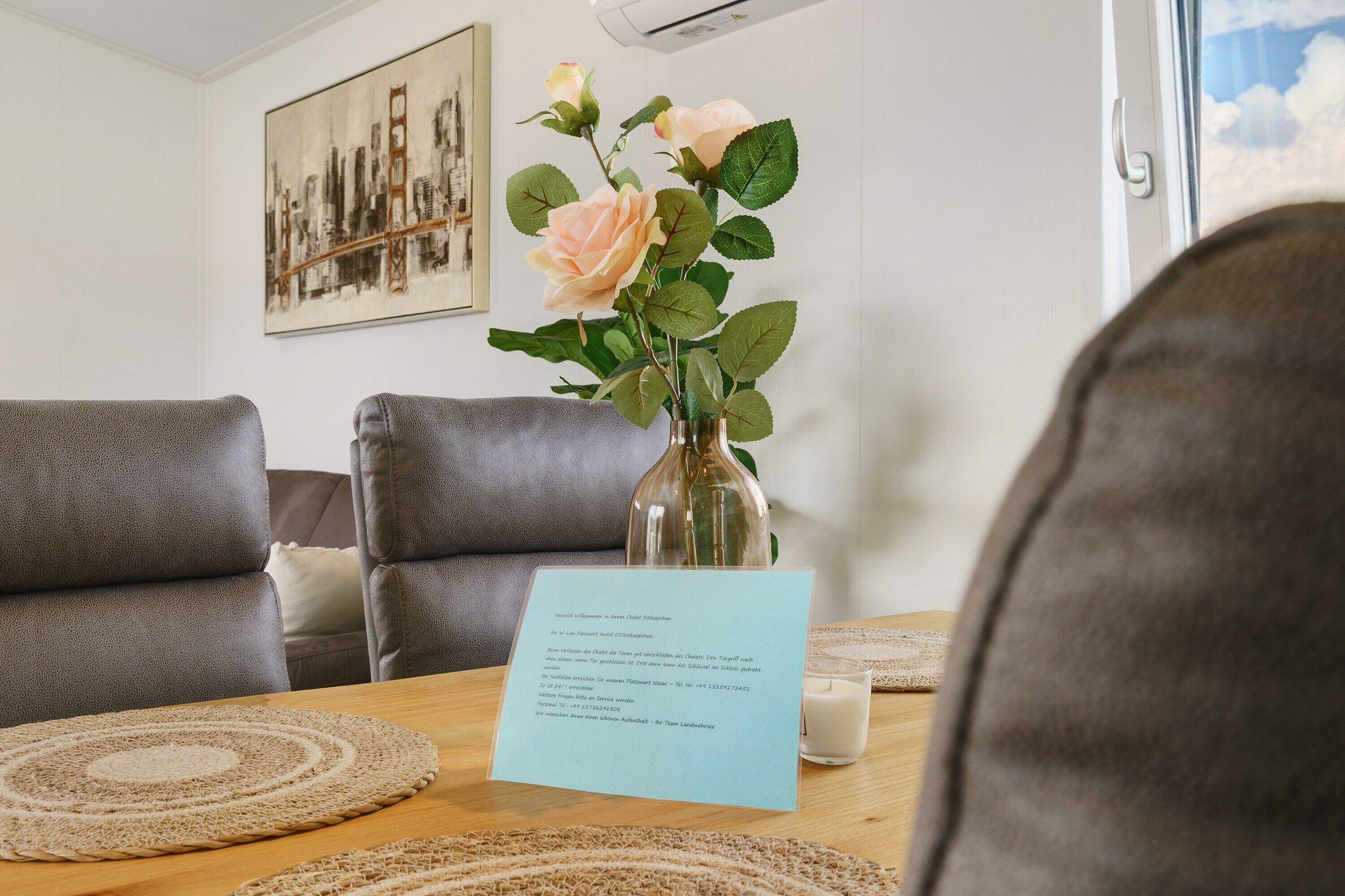 Et værelse med et træbord, en vase med blomster, et billede i ramme på væggen og en sofa.