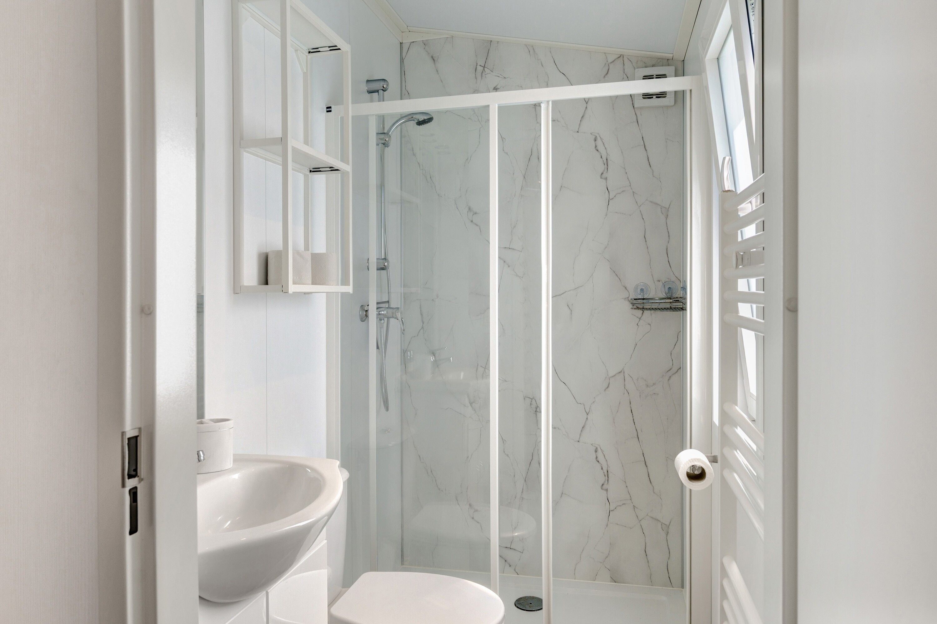 A modern bathroom with a glass-enclosed shower, a white sink, and a toilet.