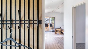 En modern inredning med en väggpanel av träribbor, en hängande hylla och utsikt över ett vardagsrum med soffa och bord.