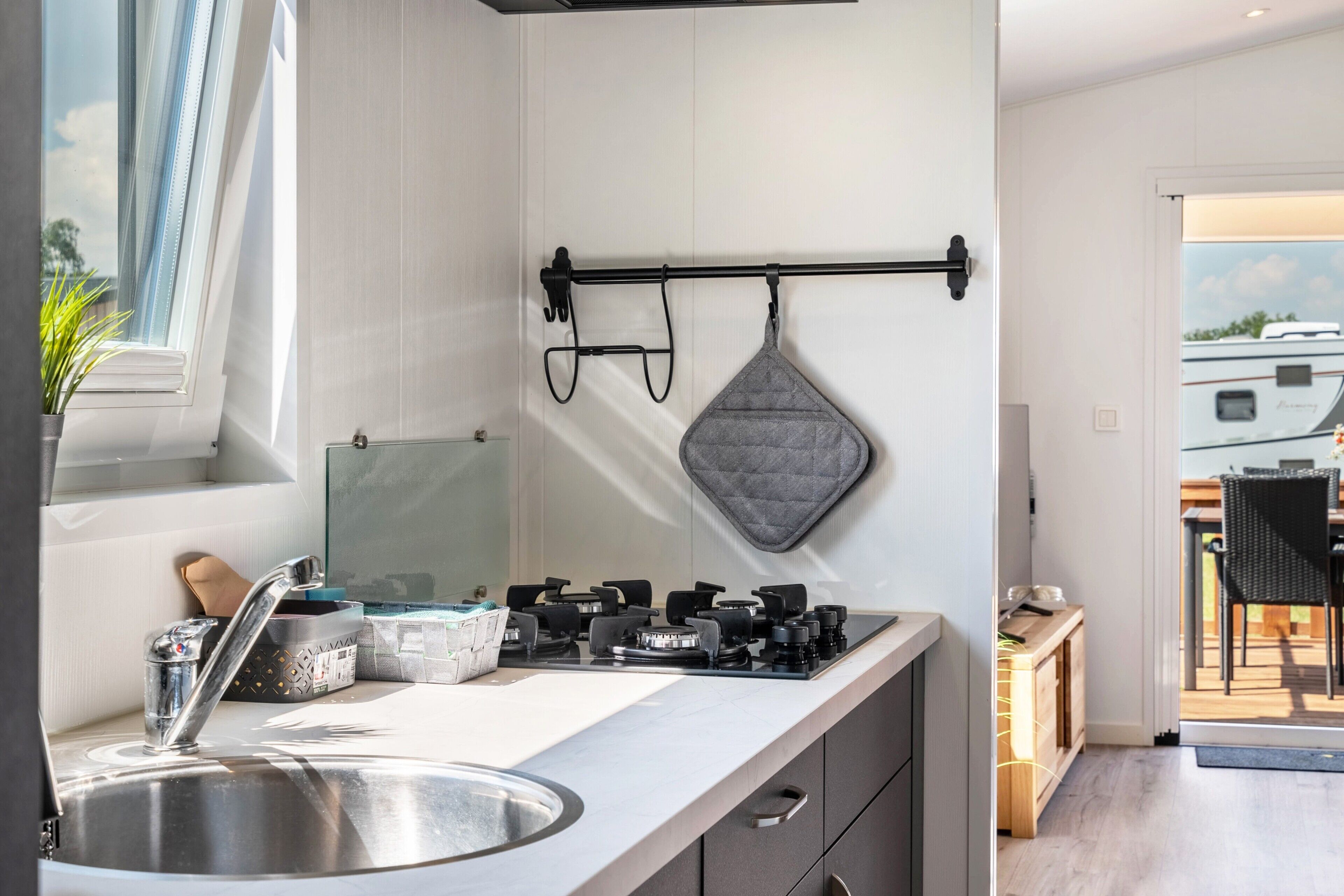 A modern kitchen with a stainless steel sink, a gas stove, and a hanging pot rack.