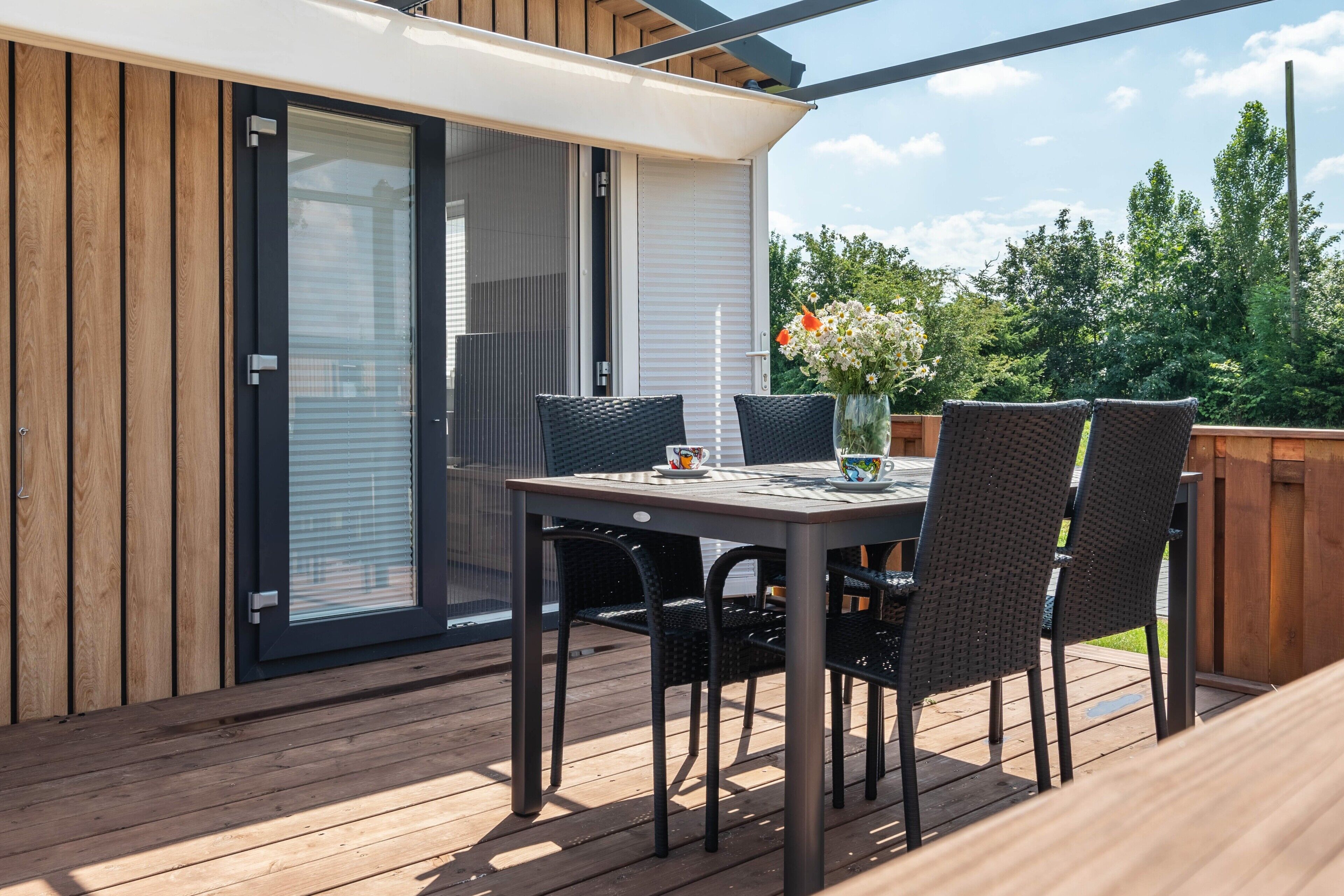 Une terrasse avec une table et des chaises, une porte-fenêtre coulissante et une clôture en bois.