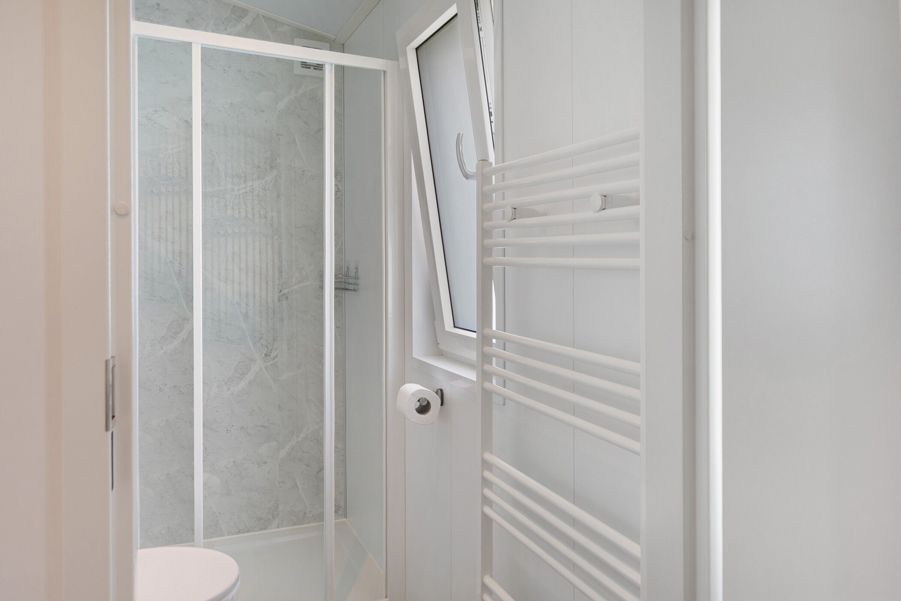 Ein Badezimmer mit Dusche, Toilette und Handtuchhalter.