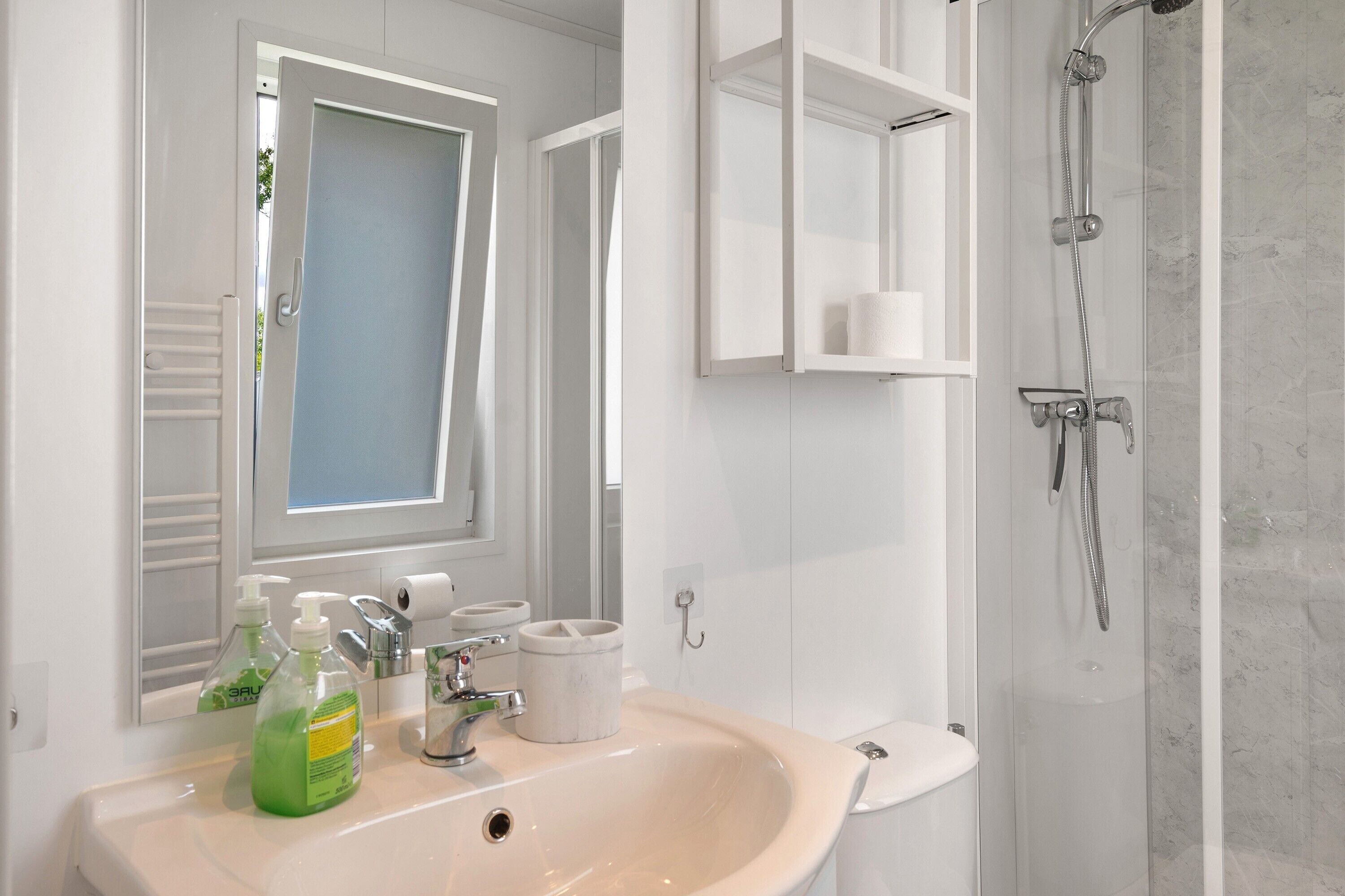A bathroom with a sink, mirror, shower, and toilet.