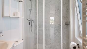 Un baño con ducha, inodoro, lavabo y ventana con vistas.