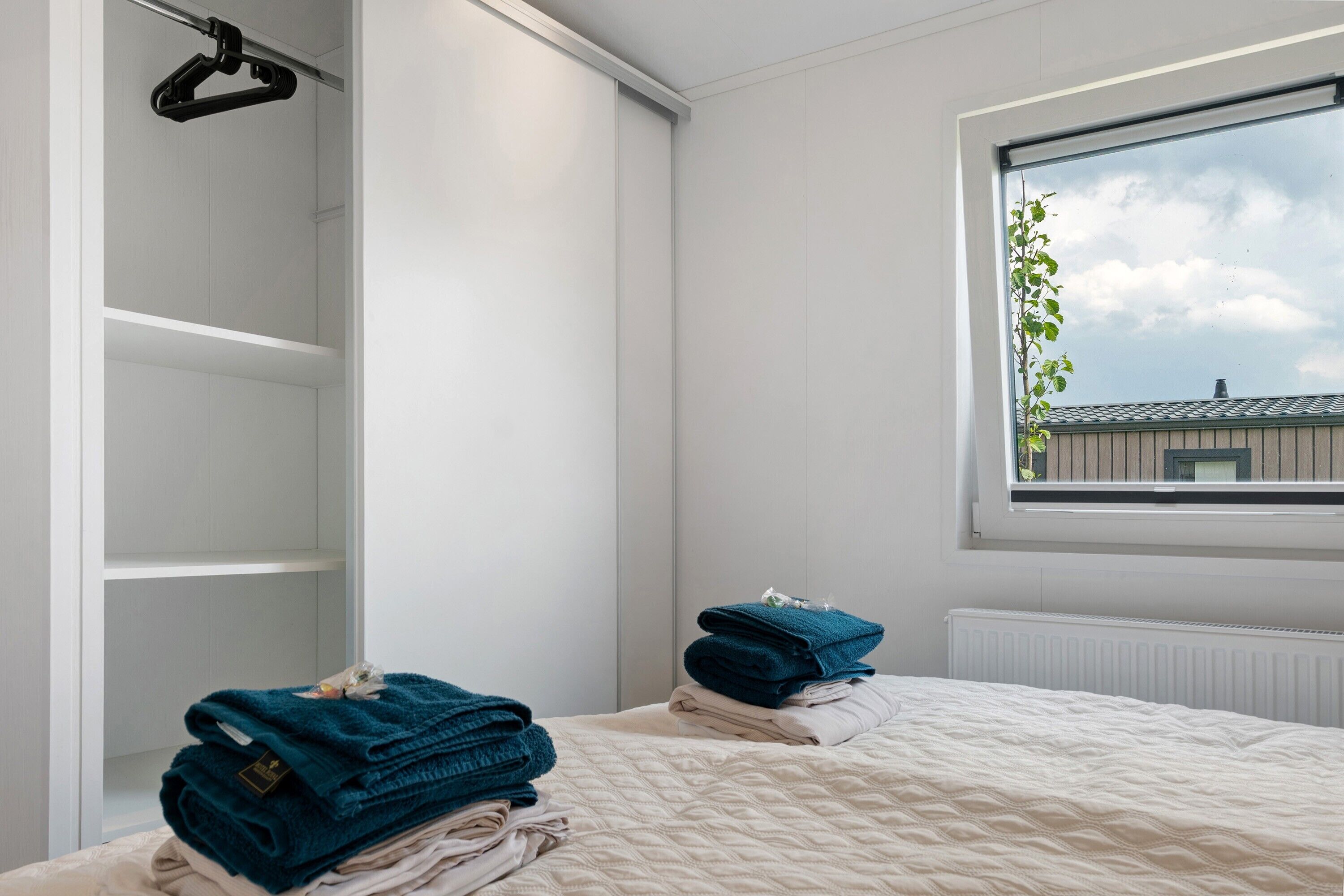 Una camera da letto con un letto, una finestra vista, un armadio e un termosifone.