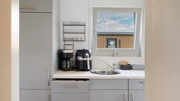 A modern kitchen with a built-in dishwasher, a coffee maker, and a window with a view of a building.
