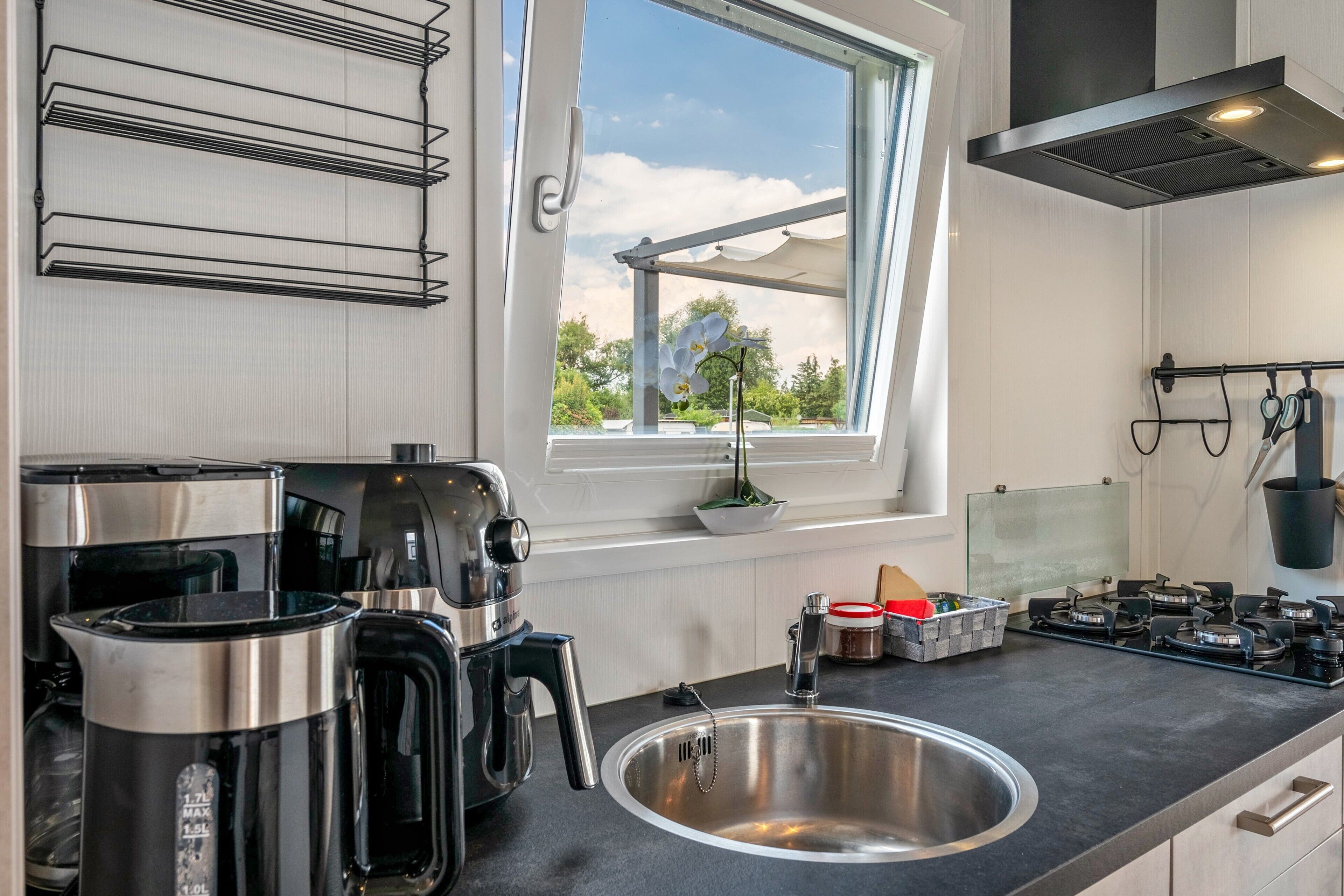 Une cuisine moderne dotée d’appareils électroménagers en acier inoxydable, d’une grande fenêtre offrant une belle vue et d’un plan de travail noir.