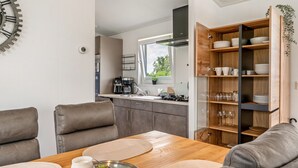A modern kitchen with a window, built-in shelves, and a dining area with a table and chairs.