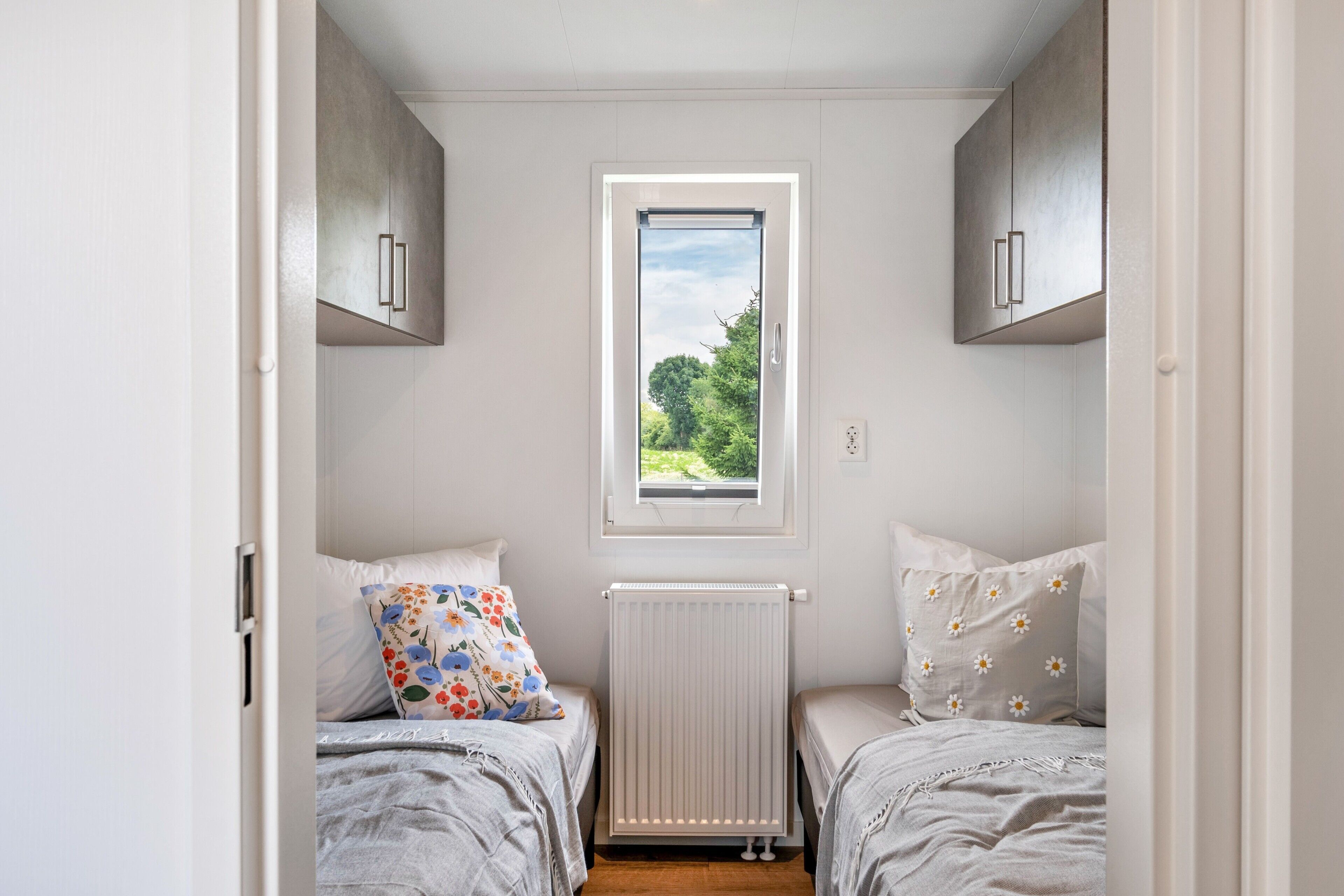 Une chambre avec deux lits, une fenêtre et un radiateur.
