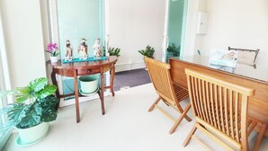 Quarto com escrivaninha de madeira, uma cadeira, uma pequena mesa com figuras e um vaso de planta.