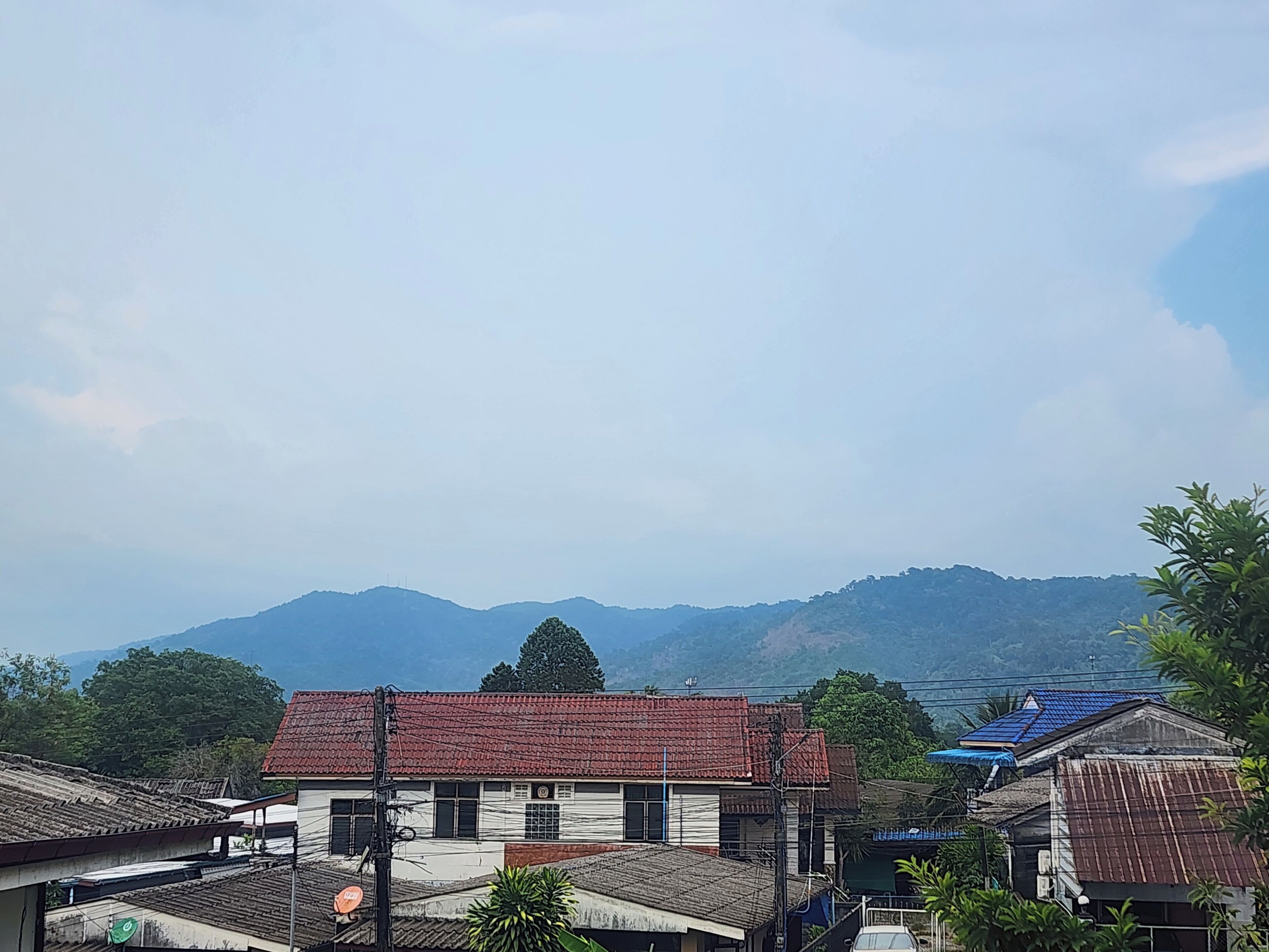A residential area with houses, a clear sky, and distant mountains.