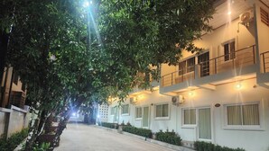 Um edifício residencial com várias varandas, um caminho de concreto e plantas em vasos ao longo da rua.