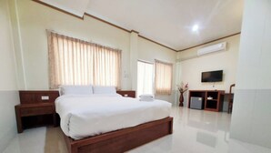 Quarto de hotel com uma cama grande, televisão, escrivaninha e uma cadeira.