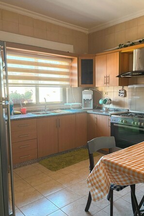 Eine Küche mit Holzschränken, einem Herd, einem Spülbecken und einem Fenster mit Jalousien.