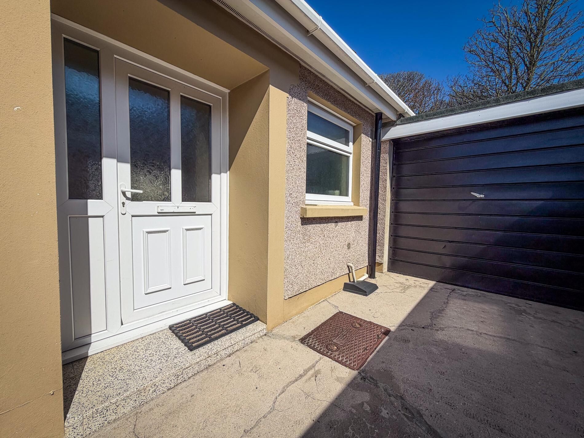A house with a front door, a window, a doormat, and a garage door.