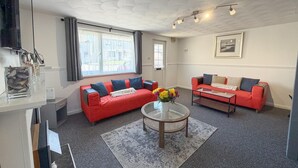 A living room with two red sofas, a glass coffee table, a large window, and a ceiling with a leaf pattern. - Pleasant View - 3 Bedroom Holiday Home - Pembroke (Pembroke)