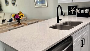 Uma cozinha moderna com bancada de granito, pia de aço inoxidável e lava-louças.