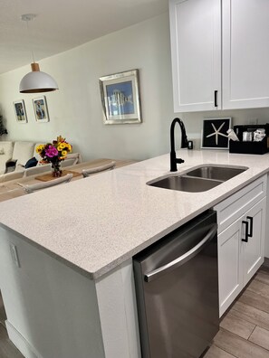 Een moderne keuken met een granieten aanrecht, een roestvrijstalen spoelbak en een vaatwasser.