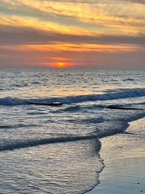 A sunset over the ocean with waves approaching the shore. - 2 bdrm condo, on the Intercostal, walk to the Gulf coast beach! (Madeira Beach)