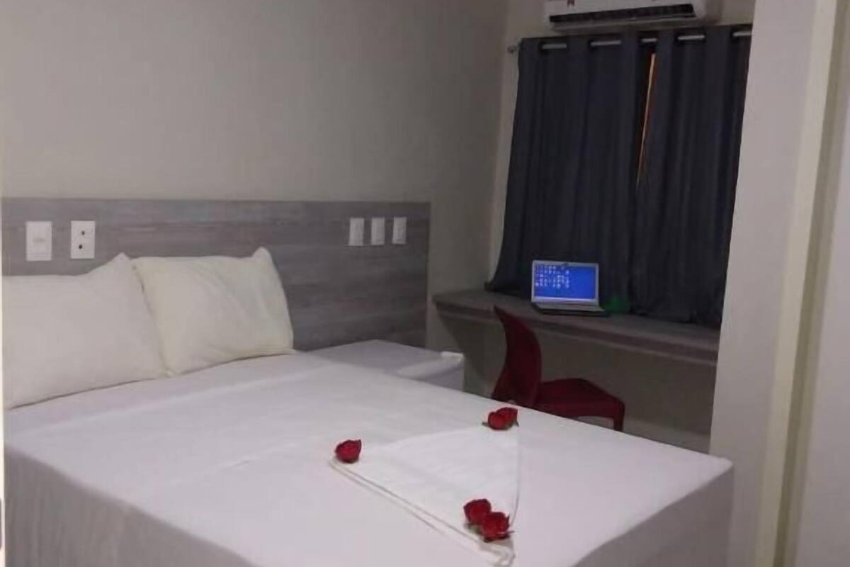 A hotel room with a bed, a desk, and a TV.
