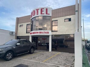 A hotel with a prominent 'HOTEL' sign, a 'BIKE CYCLE BOULEVARD' sign, and a parking area with a gray SUV. - HOTEL EXECUTIVO BOULEVARD (Mossoro)