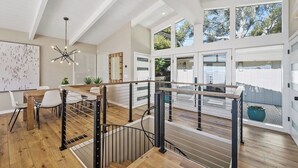 A modern interior with a wooden floor, white walls, and a staircase with metal railings. - Seacliff Ocean View Escape (Aptos)