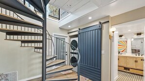 A modern interior with a spiral staircase, a sliding door, and a kitchen area. - Seacliff Ocean View Escape (Aptos)