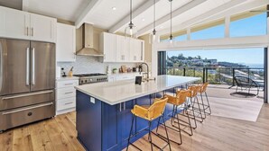 A modern kitchen with a large island, stainless steel appliances, and a view to the outdoors. - Seacliff Ocean View Escape (Aptos)