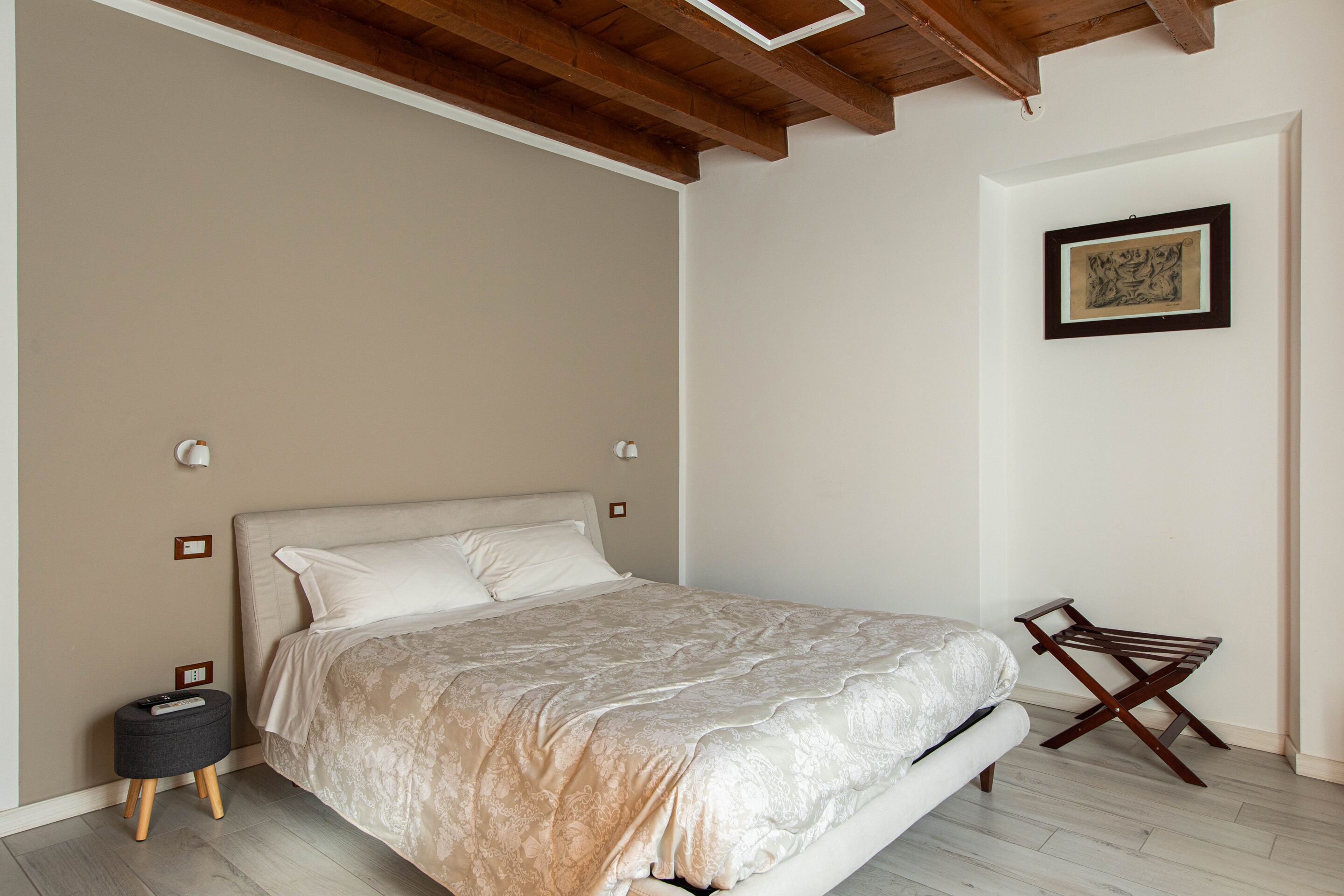 A bedroom with a bed, bedside table, and a folding chair.