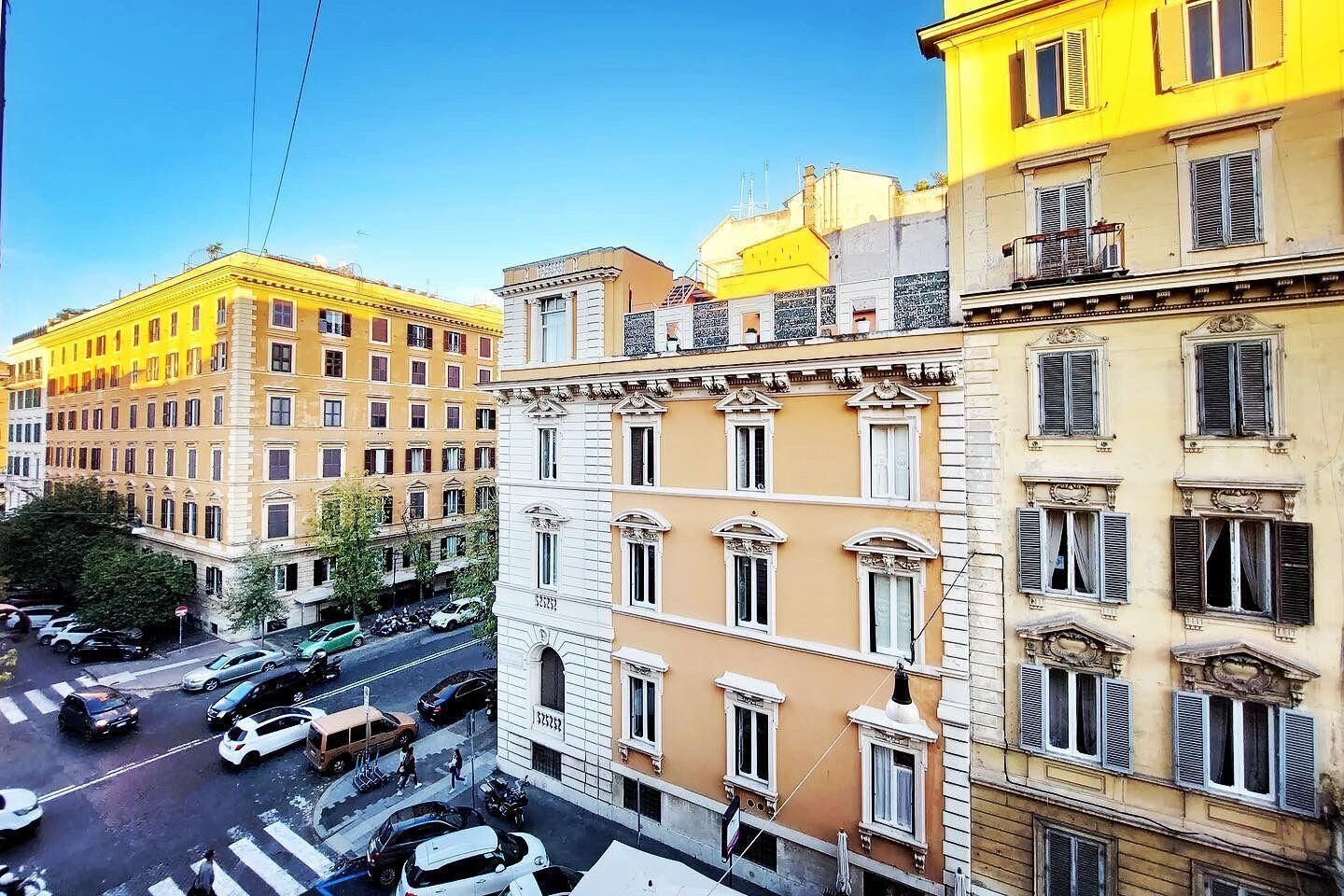 Ein mehrstöckiges Gebäude mit gelber Fassade, weißen Fensterrahmen und einem Balkon im oberen Stockwerk.